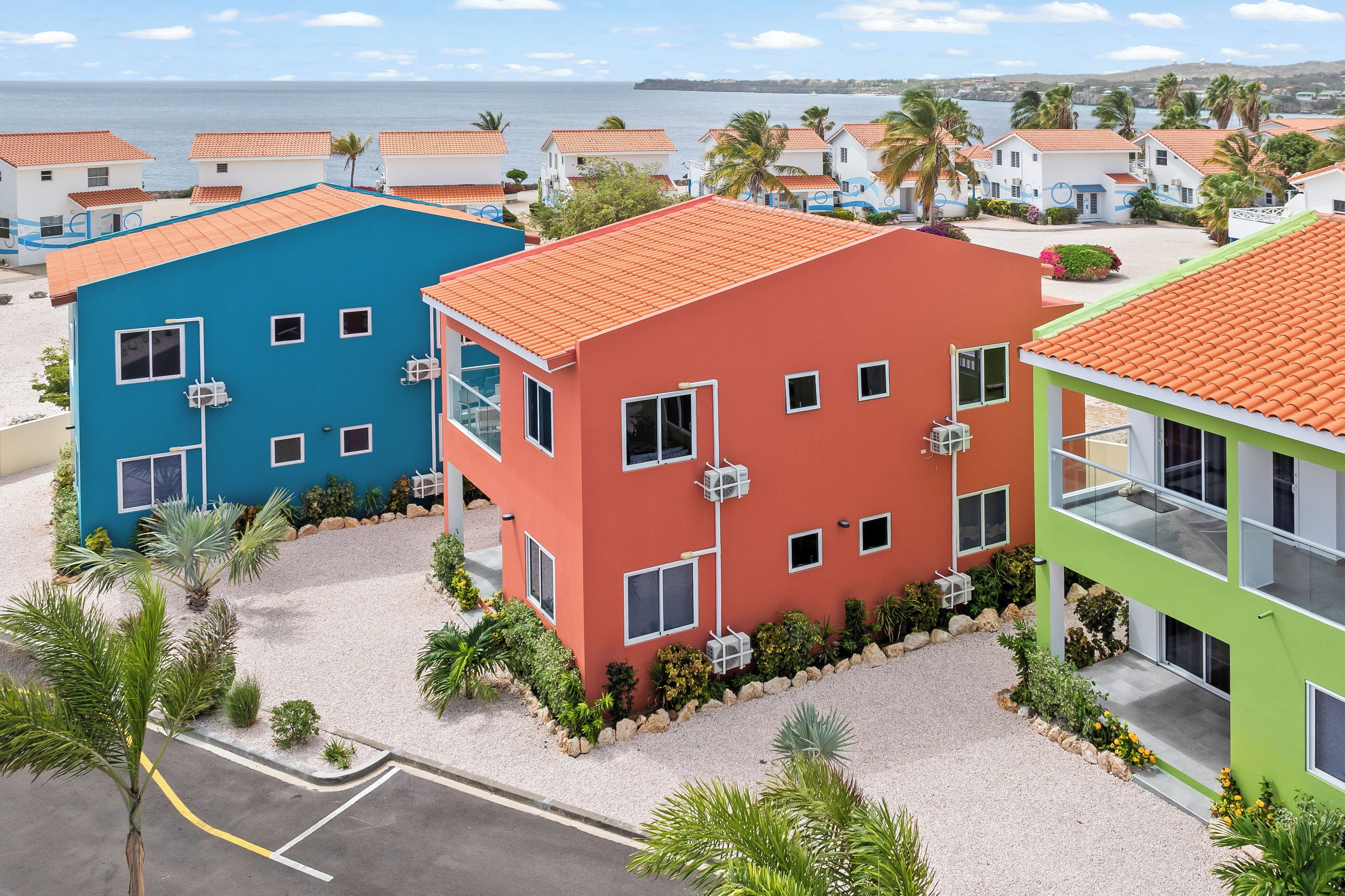 Un hotel frente al mar con edificios coloridos, una playa de arena y vistas al océano.