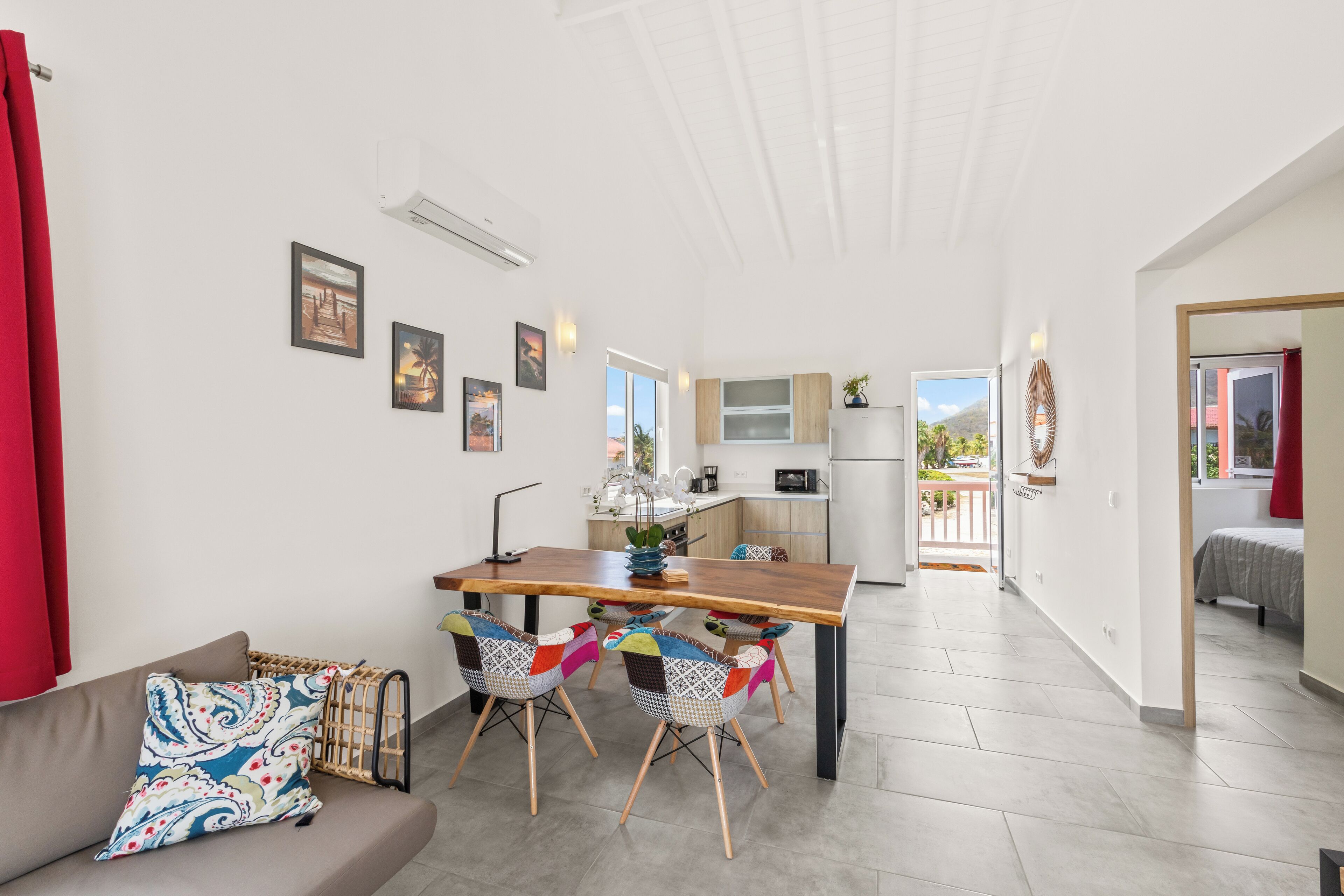 A modern kitchen with a dining area, a sofa, and a view of the outdoors.
