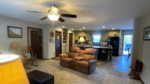 A living room with a ceiling fan, a sofa, a coffee table, and a lamp.