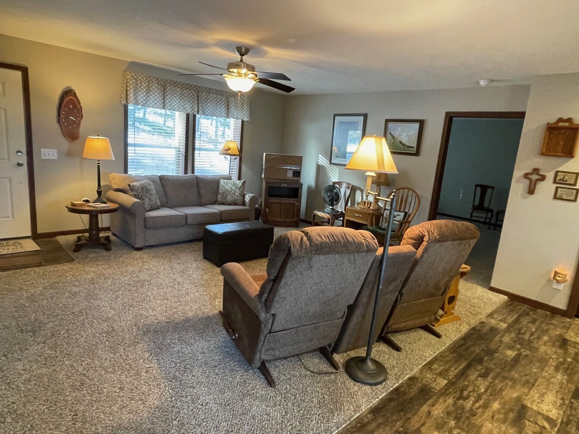 Un salon comprenant un canapé, deux fauteuils, une table basse, un lampadaire et un ventilateur de plafond.