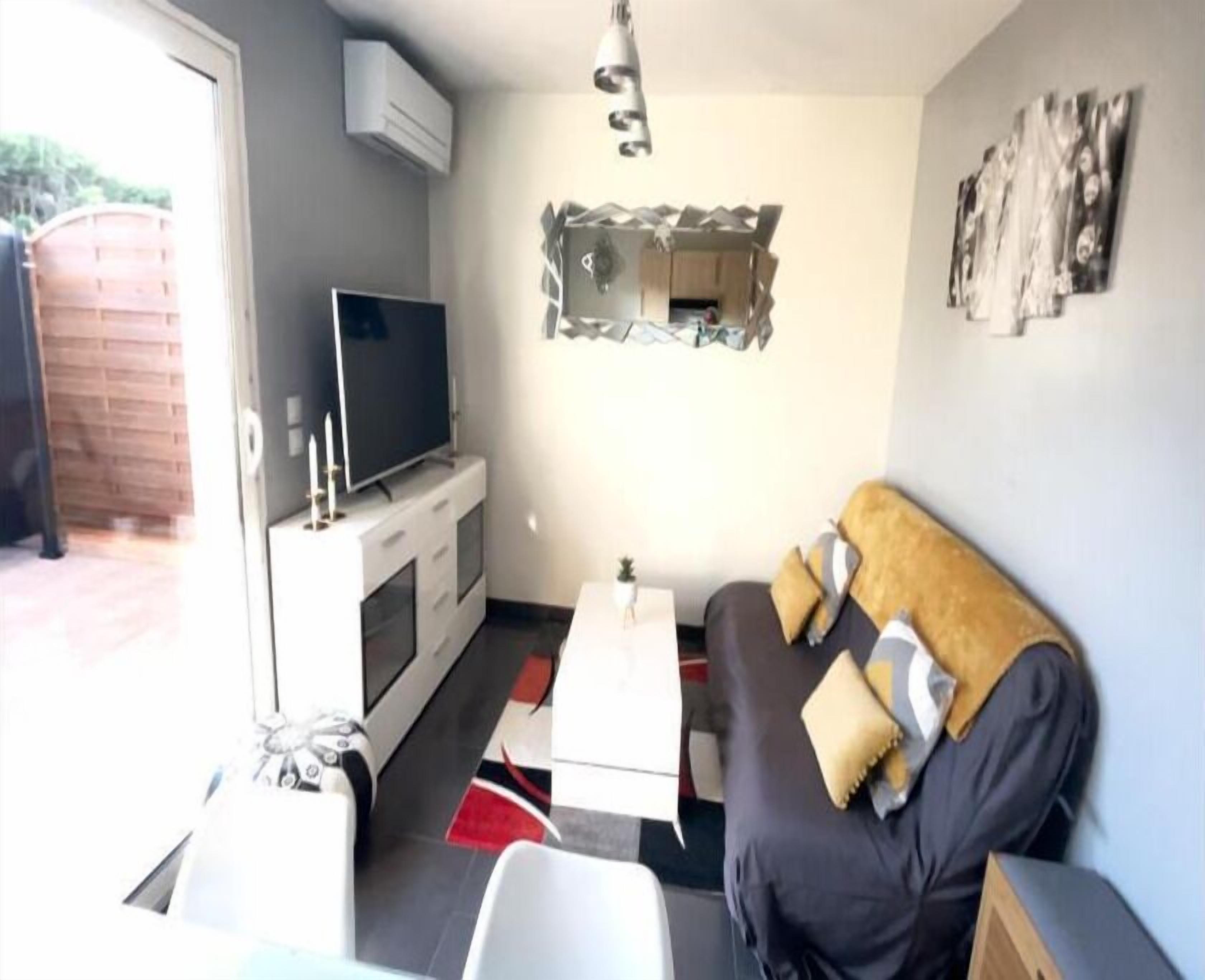 Un salon avec un canapé, un téléviseur et une petite table.