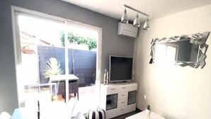 A modern living room with a flat-screen TV, a dining table, and a sofa. - Apartment T2 - 40M² (40M²) (Saint-Martin-de-Seignanx)