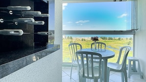 A balcony with a view of the beach, a grill, and a table with chairs. - Resid. Clube Mar Grosso-Laguna - LAG100 (Laguna)