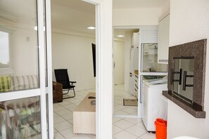 Une cuisine moderne équipée d’un four encastré, d’un four à micro-ondes et d’un réfrigérateur. On y trouve également un banc en bois et une chaise dans l’espace repas.