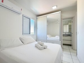 A hotel room with a bed, a large mirror, a wardrobe, and a window with blinds. - Resid. Clube Mar Grosso-Laguna - LAG100 (Laguna)