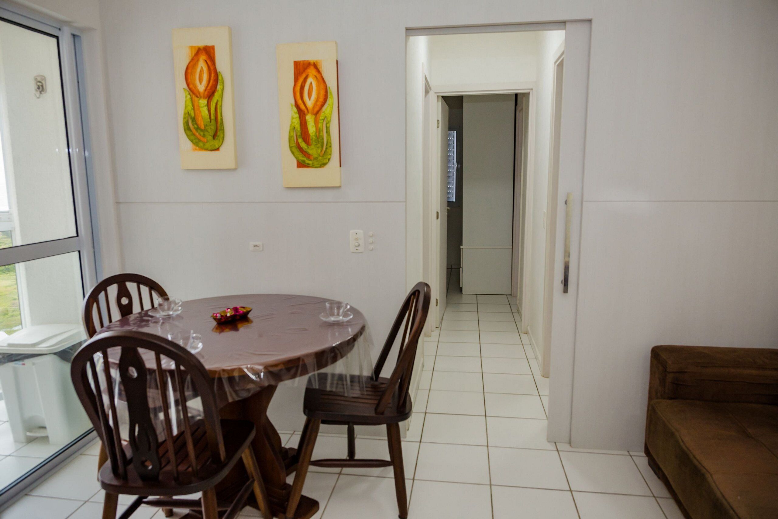Un coin repas avec une table ronde, quatre chaises et deux tableaux accrochés au mur.