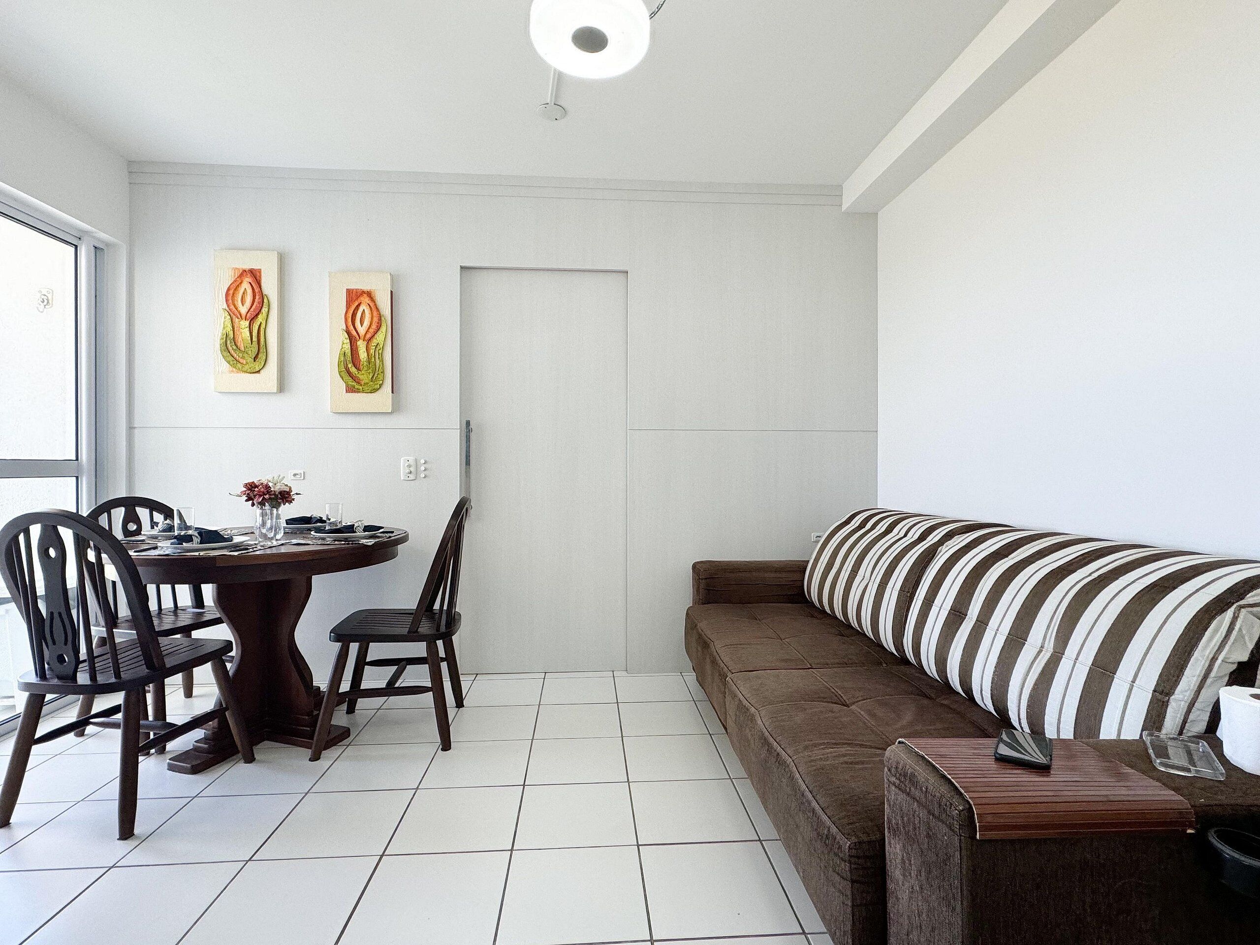 Un coin repas avec une table ronde, deux chaises et deux œuvres d’art accrochées au mur.