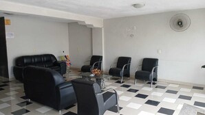 A waiting area with black leather sofas and chairs, a marble coffee table, and a wall-mounted fan. - Gutemberg Palace Hotel (Nova Serrana)