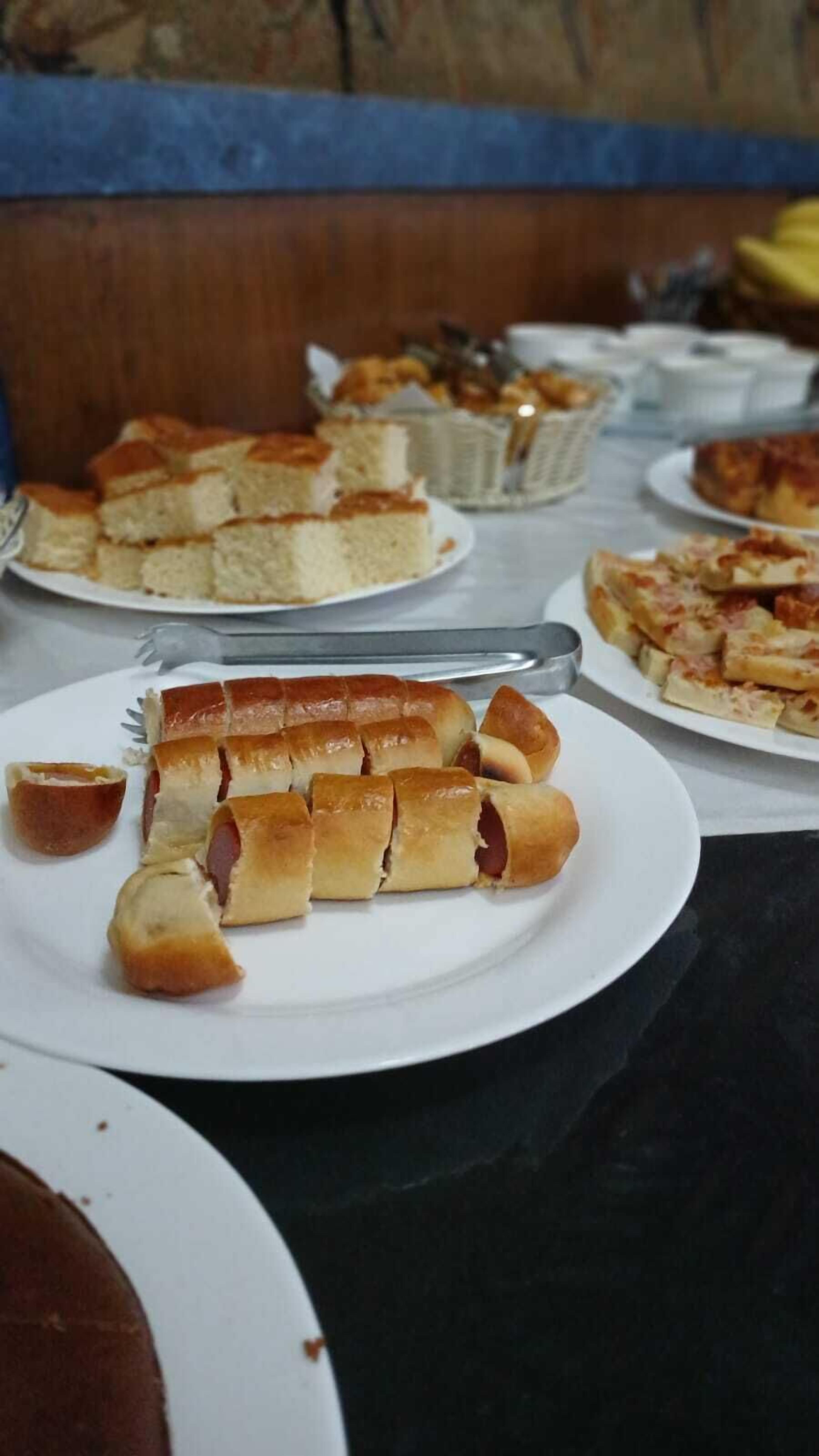 Una mesa de comedor con diversos platos, incluyendo pan, un perro caliente y una pizza.