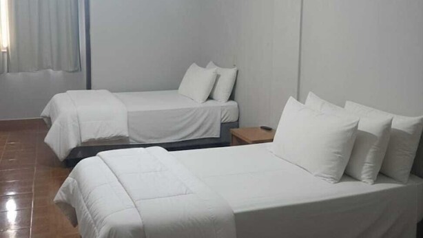 A room with two beds, a ceiling fan, and a window with curtains. - Gutemberg Palace Hotel (Nova Serrana)