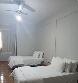 A room with two beds, a ceiling fan, and a window with curtains. - Gutemberg Palace Hotel (Nova Serrana)