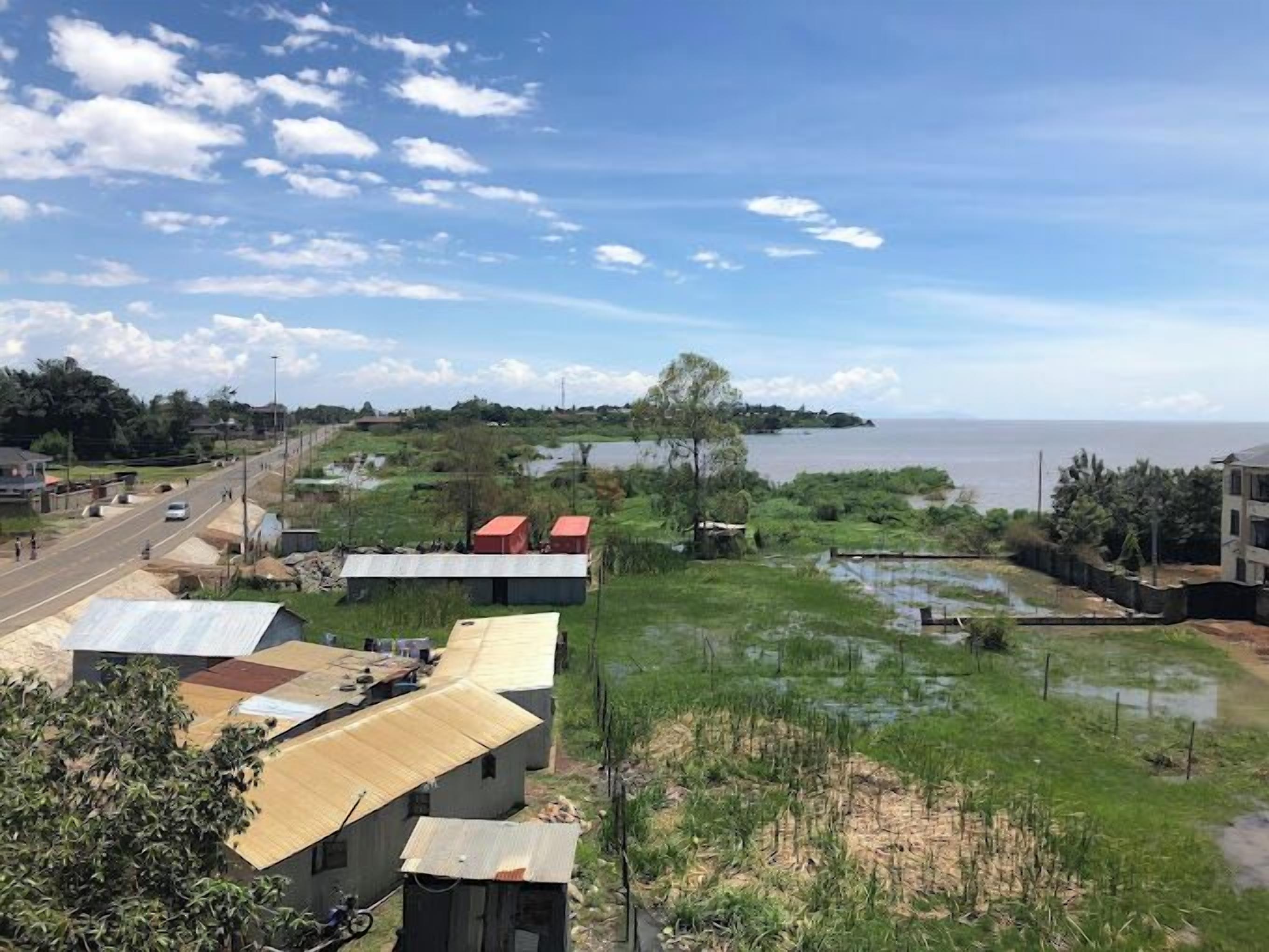 Zona costera con una carretera, edificios pequeños y una masa de agua.