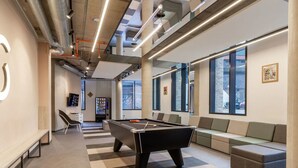 Zona de billar moderna en interior con asientos y una máquina expendedora.
