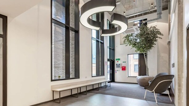 Un interior moderno con ventanas amplias, un banco, una lámpara circular original y una planta en maceta.