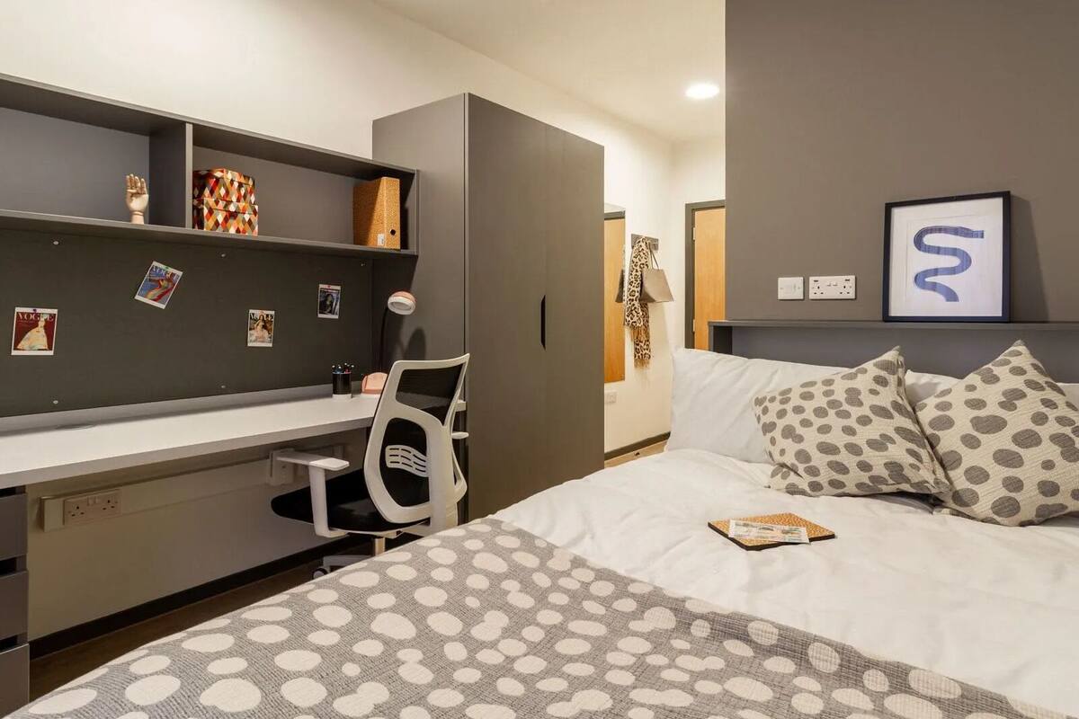 A modern bedroom with a bed, a desk, and a wardrobe.