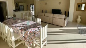 A spacious living area with a dining table surrounded by chairs, a sofa, and a television.