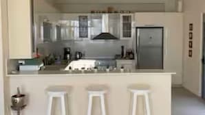 A modern kitchen with a central island, bar stools, and a chandelier.
