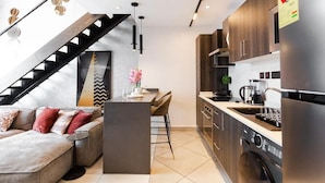 A modern kitchen with a built-in oven, a coffee maker, and a washing machine. - Premium Suite (Accra)