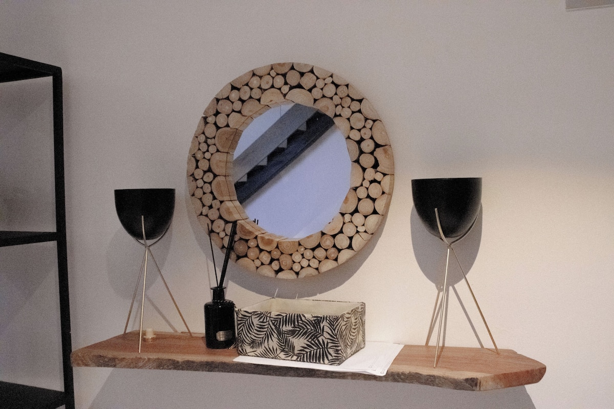 A wooden shelf with a mirror, two black vases, and a patterned box.