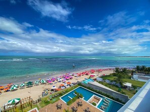 Un resort frente a la playa con piscina, sombrillas y vistas al océano.