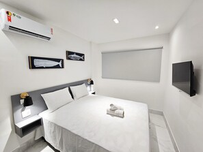 A modern hotel room with a bed, bedside tables, a wall-mounted TV, and artwork. - Mirante de Porto - Porto de Galinhas (Ipojuca)