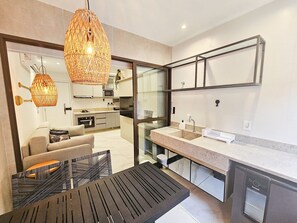 A modern kitchen with a dining area, a built-in oven, and a large window. - Mirante de Porto - Porto de Galinhas (Ipojuca)
