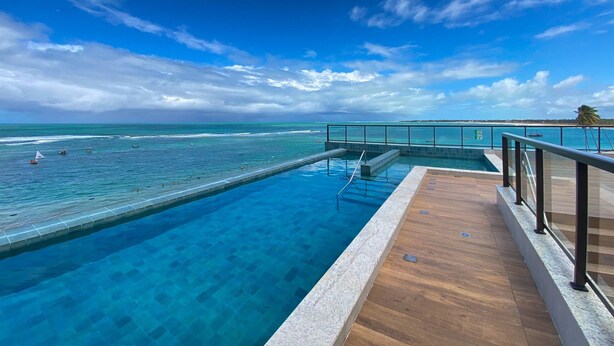 En klarblå himmel, en swimmingpool och utsikt över havet.