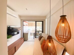 Una sala de estar moderna con sofá, televisor e iluminación colgante.