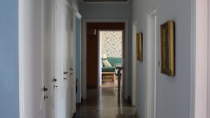 Un couloir avec des portes blanches, un sol en marbre et un lit à l’arrière-plan.
