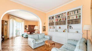 Un salon doté d’un plancher en bois, de deux canapés bleu clair, d’une petite table en bois, d’une bibliothèque et d’une grande porte en arc donnant sur une autre pièce.