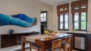 A kitchen with a wooden dining table, two chairs, a fruit bowl, and a painting on the wall. - Beautiful Mediterranean-Style Penthouse with an Oceanview Balcony (Las Catalinas)
