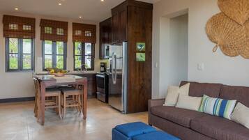 A modern kitchen with a built-in refrigerator, wooden cabinets, and a dining area with a table and chairs.