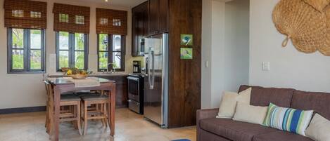 A modern kitchen with a built-in refrigerator, wooden cabinets, and a dining area with a table and chairs.