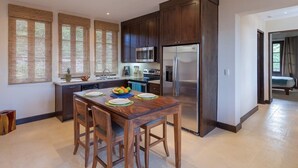 A modern kitchen with dark wood cabinets, stainless steel appliances, and a central island with seating. - Beautiful Mediterranean-Style Penthouse with an Oceanview Balcony (Las Catalinas)