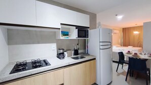 Una cucina compatta con piano cottura a gas, lavello, microonde e frigorifero. C'è un'area pranzo con tavolo e sedie.