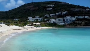 A beach with clear turquoise water, white sandy shore, and buildings on a hillside. - AZUR -  NEW SEA SIDE DR, 4 BR, 4.5 BA -  WALK TO  INDIGO BEACH (Sint Maarten)