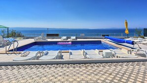A pool area with lounge chairs and a view of the sea. - Seaside Apartment with Pool (Split)