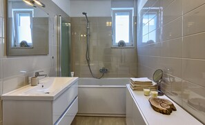 Une salle de bain moderne avec une baignoire, une douche à parois de verre et un meuble-lavabo avec un évier et un miroir.
