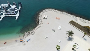 An aerial view of a beach with a pier, sun loungers, and palm trees. - Seaside Apartment with Pool (Split)