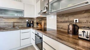 A modern kitchen with white cabinets, a wooden countertop, a stainless steel toaster, and a coffee maker. - Seaside Apartment with Pool (Split)