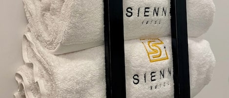 A towel rack with four white towels, each with a logo and the word "SIENN" printed on them.