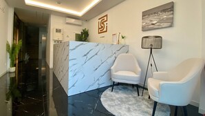 A reception area with a marble counter, two white armchairs, a fluffy rug, a floor lamp, and a painting on the wall. - SIENNA Hotel (Rio Maior)