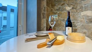 A table with a bottle of wine, a glass, cheese, and a wooden cheese knife. - SIENNA Hotel (Rio Maior)