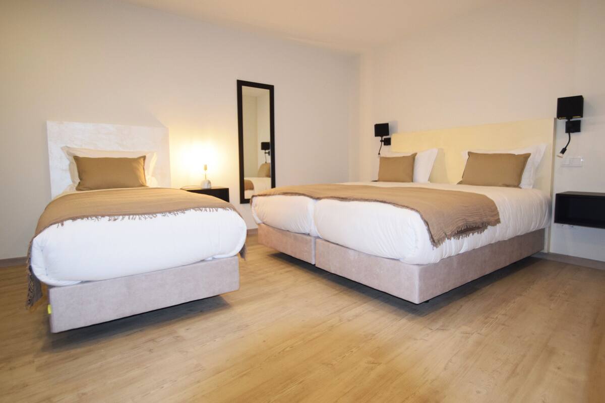 A double room with two beds, each with a headboard, bedside tables, and lamps.
