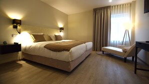A modern hotel room with a large bed, bedside lamps, a desk, and a view of the outdoors. - SIENNA Hotel (Rio Maior)