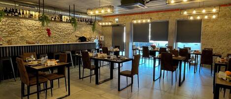 A restaurant with a bar area, stone walls, and multiple tables and chairs.