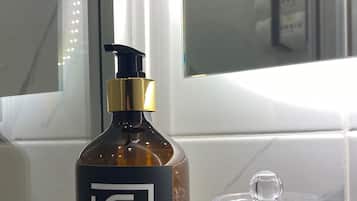 A bottle of hand soap and a glass container on a wooden tray.