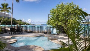 Un espace piscine doté d’un jacuzzi, de chaises longues et offrant une vue sur l’océan.
