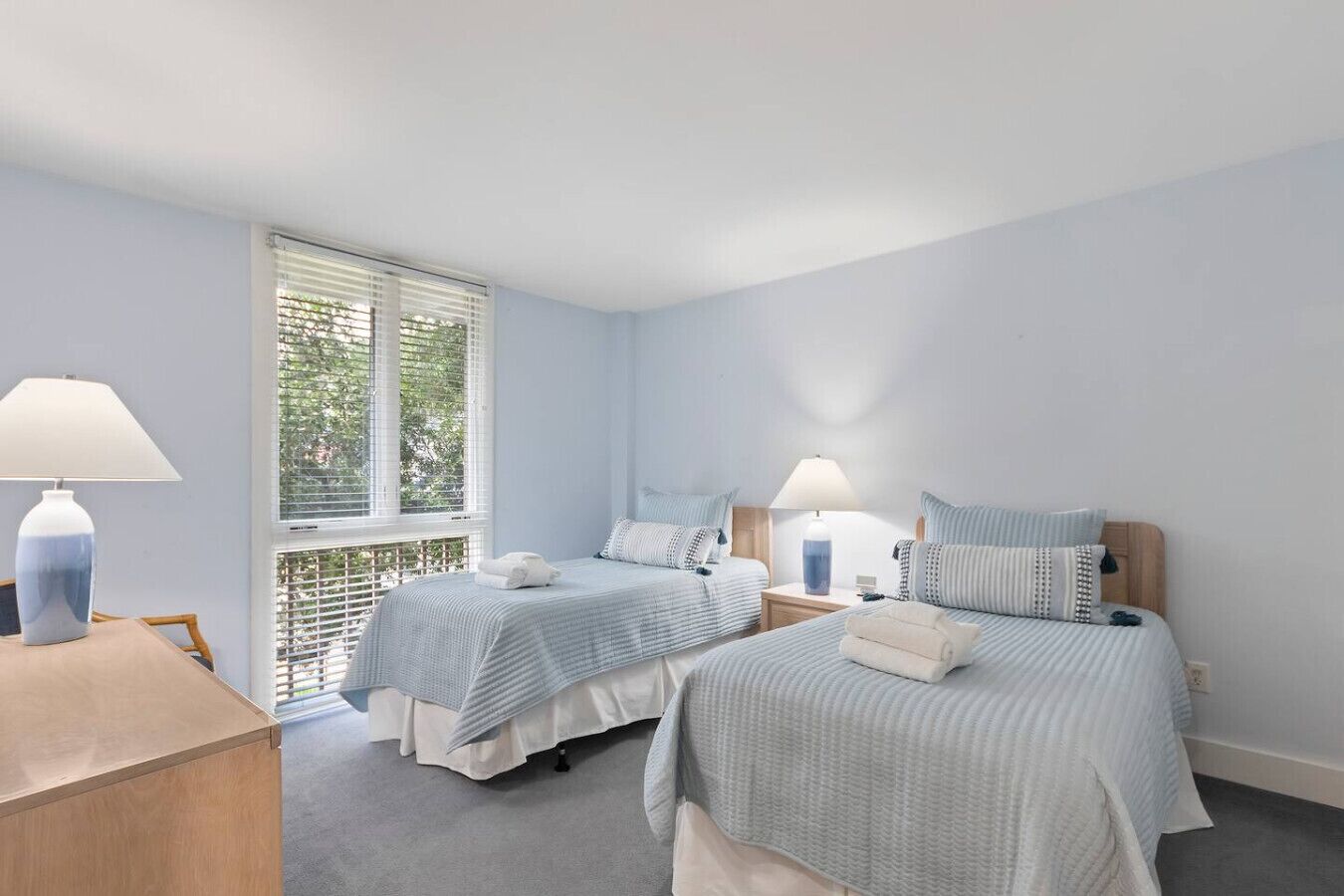 Un dormitorio con dos camas individuales, un escritorio y una ventana con persianas.