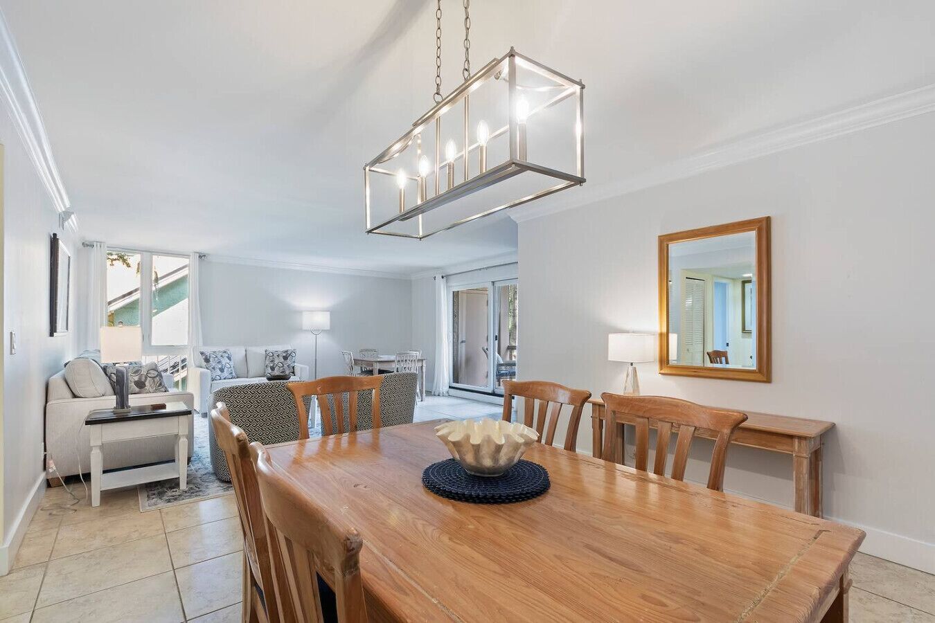 Comedor con mesa de madera, sillas y un cuenco decorativo en el centro. Una lámpara colgante ilumina la mesa.